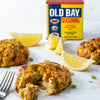 Crab cakes with lemon wedges and Old Bay seasoning.