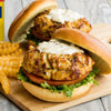 Two crab cakes on buns with lettuce, tomato, and a creamy sauce.
