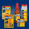 A collection of five Old Bay products including a packet of Old Bay Regular Crab Cake Seasoning Mix 1.24 Oz displayed against a solid blue background.