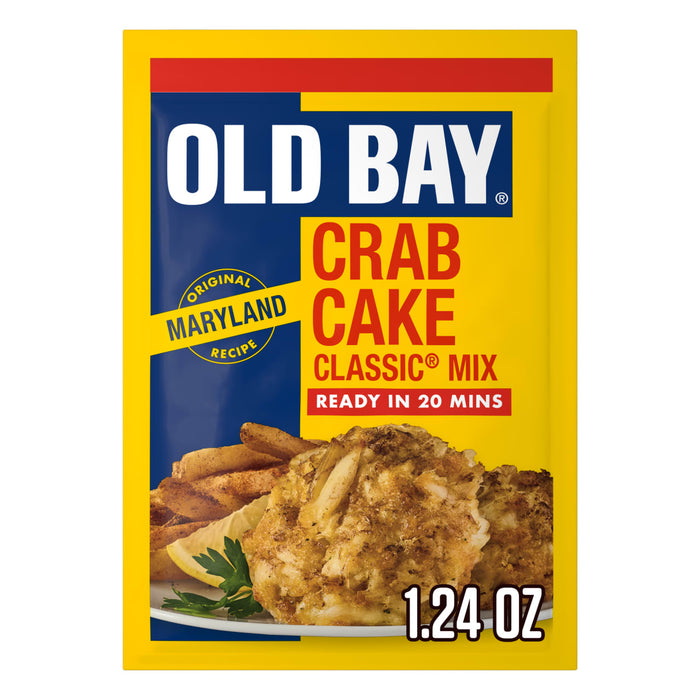 A yellow and blue packet of Old Bay Regular Crab Cake Seasoning Mix 1.24 Oz featuring a photo of prepared crab cakes served with fries and a lemon wedge.