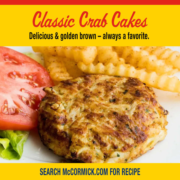 A golden brown crab cake served with crinkle cut fries and a tomato slice as a serving suggestion for Old Bay Regular Crab Cake Seasoning Mix 1.24 Oz.