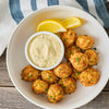 A white bowl filled with golden brown crab cake bites prepared with Old Bay Regular Crab Cake Seasoning Mix 1.24 Oz served alongside a small dish of creamy tartar sauce and fresh lemon wedges.