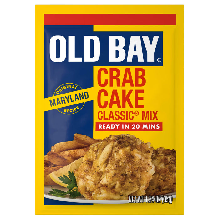 A yellow and blue packet of Old Bay Regular Crab Cake Seasoning Mix 1.24 Oz featuring a photo of prepared crab cakes served with fries and a lemon wedge.