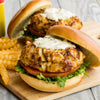 Two crab cakes on buns with lettuce, tomato, and a creamy sauce.