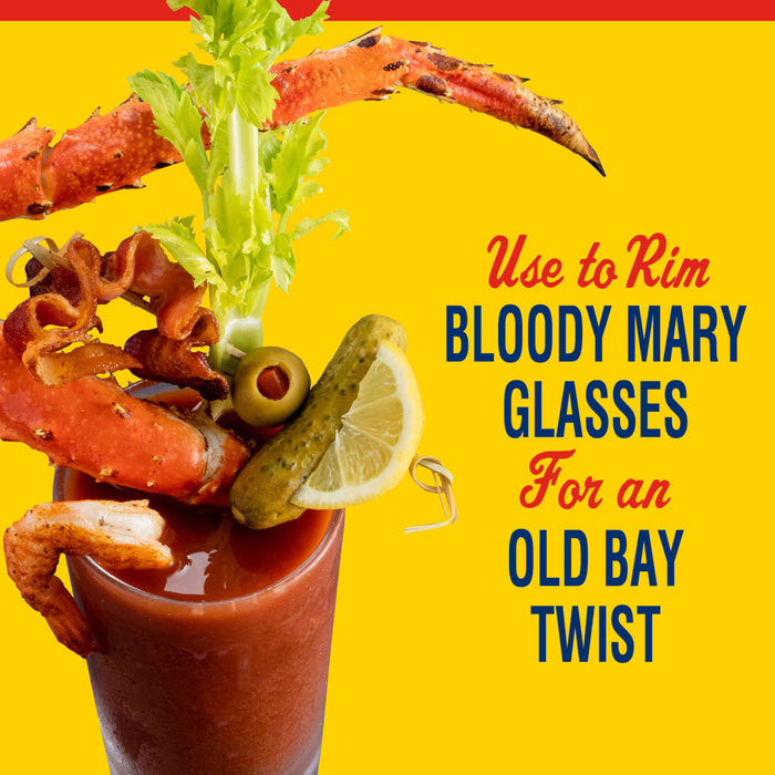 A Bloody Mary garnished with crab legs bacon celery olives a pickle and a lemon wedge with text that says Use to rim Bloody Mary glasses for an Old Bay twist.