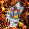 A container of Old Bay Seasoning sits on a table with cooked crabs, potatoes, and lemons.