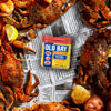 A container of Old Bay Seasoning sits on a table with cooked crabs, potatoes, and lemons.