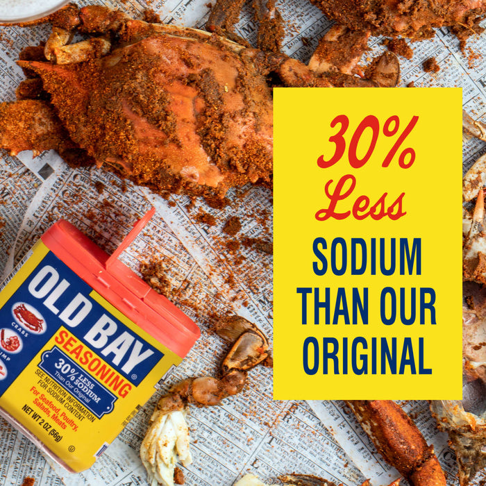 A can of Old Bay Seasoning with a crab on the front, surrounded by crab legs and a yellow sign that says 30% Less Sodium Than Our Original.