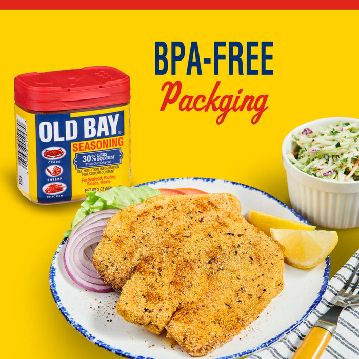 A container of Old Bay Seasoning next to a plate of fried fish with lemon wedges and red onion.