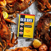 A can of Old Bay Seasoning is surrounded by cooked crabs and lemon wedges.