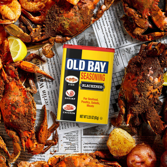 A can of Old Bay Seasoning is surrounded by cooked crabs and lemon wedges.