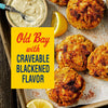A tray of blackened crab cakes seasoned with Old Bay, served with lemon wedges and a dipping sauce.