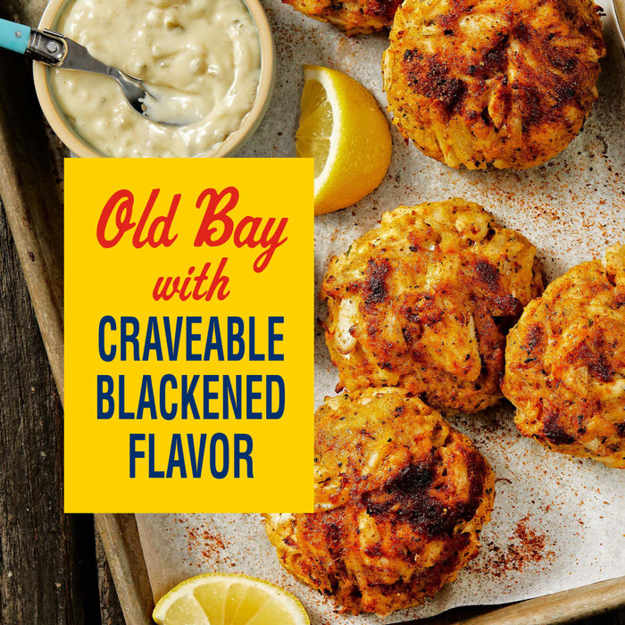 A tray of blackened crab cakes seasoned with Old Bay, served with lemon wedges and a dipping sauce.
