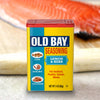 A container of Old Bay Lemon &amp; Herb Seasoning is displayed in front of a piece of salmon.