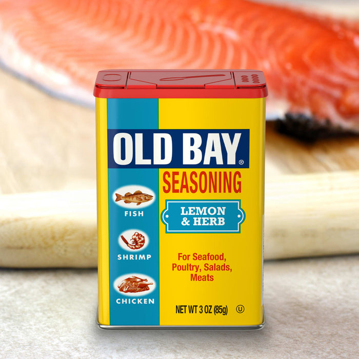 A container of Old Bay Lemon &amp; Herb Seasoning is displayed in front of a piece of salmon.