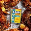 A can of Old Bay Seasoning is surrounded by cooked crabs and seafood, suggesting its use as a flavorful spice for seafood dishes.