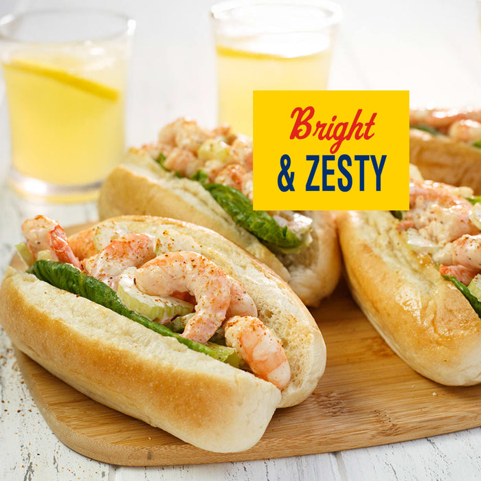 Bright and Zesty shrimp rolls are displayed on a wooden board with lemonade.
