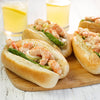 A close-up of shrimp rolls with asparagus on a wooden board, accompanied by glasses of lemonade.