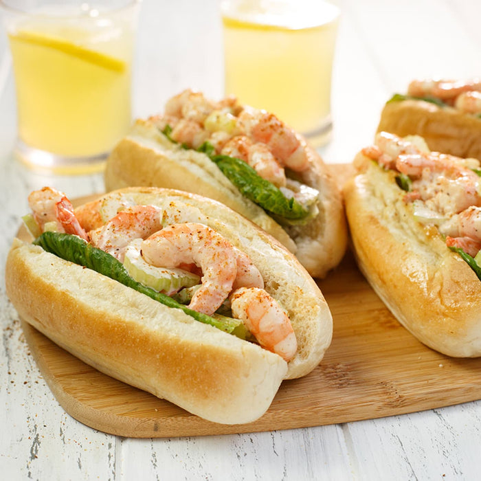 A close-up of shrimp rolls with asparagus on a wooden board, accompanied by glasses of lemonade.
