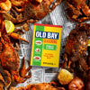 A can of Old Bay Seasoning is surrounded by cooked crabs and potatoes, suggesting its use in seafood boils.