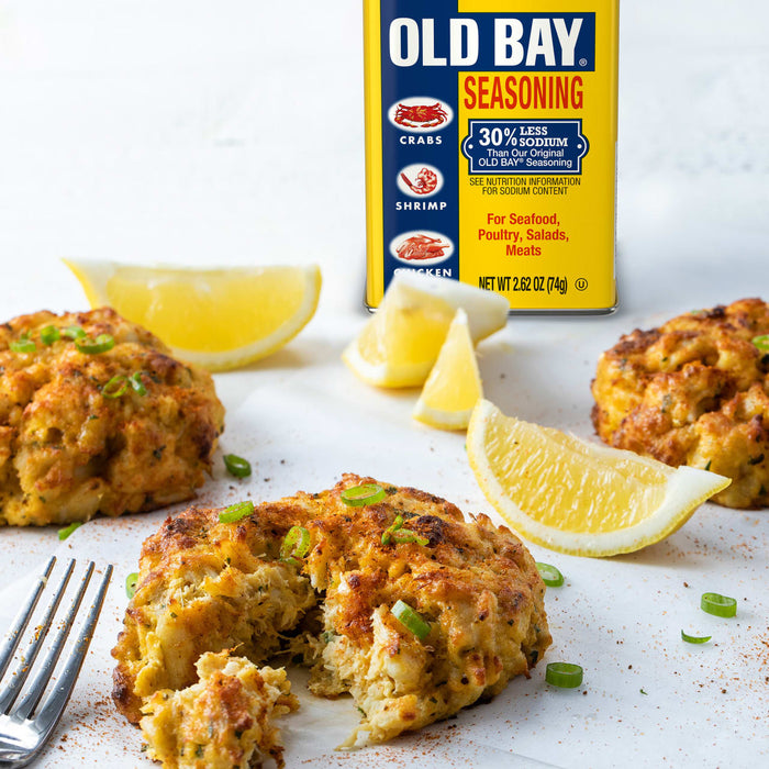 A close-up of crab cakes seasoned with Old Bay seasoning and garnished with lemon wedges.