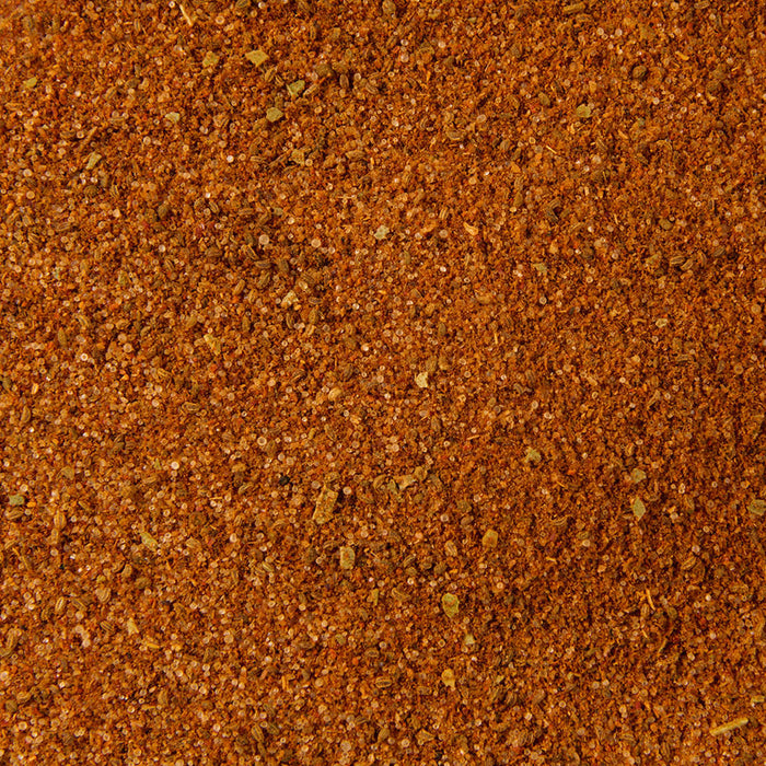 The image displays a close-up of Old Bay Seasoning Less Sodium 2.62 Oz, a reddish-brown spice blend with visible granular pieces and small green specks.