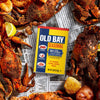 A can of Old Bay Seasoning is surrounded by cooked crabs and lemon wedges.