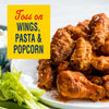 A plate of saucy chicken wings with celery and blue cheese dip, accompanied by text that suggests tossing the sauce on wings, pasta, and popcorn.