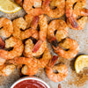 A close-up of seasoned shrimp with lemon wedges and cocktail sauce, perfect for an appetizer or snack.