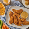 A platter of crispy breaded chicken tenders seasoned with Old Bay Black Bird Seasoning 6.5 Oz is served alongside a creamy dipping sauce and a side of fresh celery and carrots.