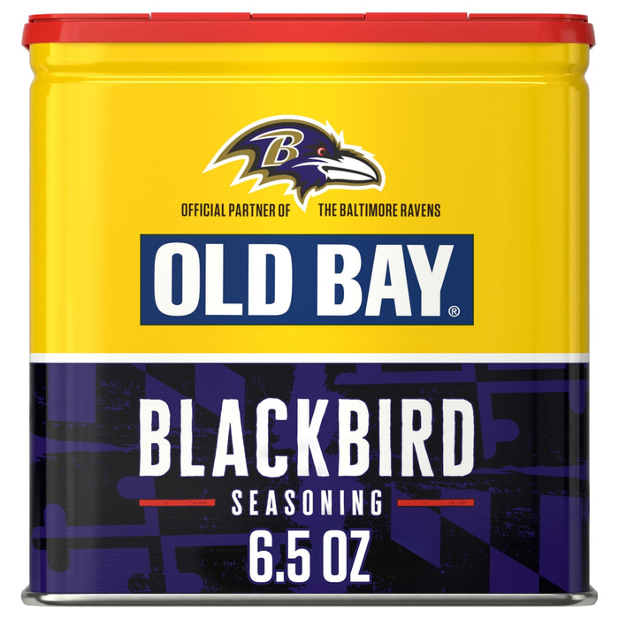 A yellow and purple tin of Old Bay Black Bird Seasoning, 6.5 Oz featuring the Baltimore Ravens logo as an official partner.