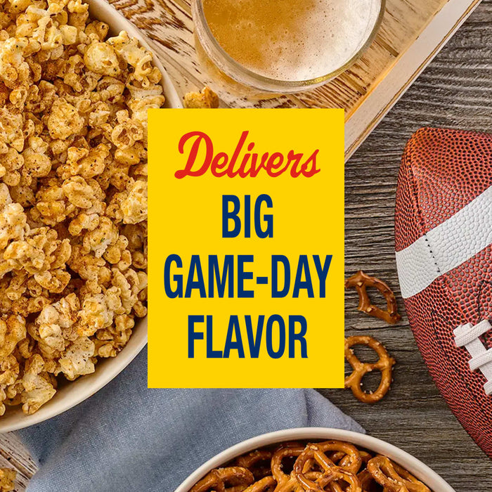 A bowl of popcorn seasoned with Old Bay Black Bird Seasoning, 6.5 Oz sits on a wooden table next to a football and pretzels for a game day snack.