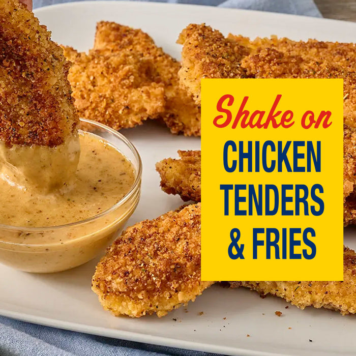A golden brown chicken tender is dipped into a creamy sauce alongside a platter of crispy chicken pieces prepared with Old Bay Black Bird Seasoning 6.5 Oz.
