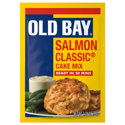 A yellow and blue packet of Old Bay Regular Salmon Seasoning Mix 1.34 Oz featuring a prepared salmon cake served with green beans and a side of dipping sauce.