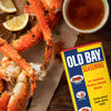 A can of Old Bay seasoning next to a plate of crab legs.