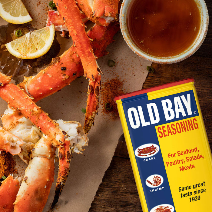 A can of Old Bay seasoning next to a plate of crab legs.