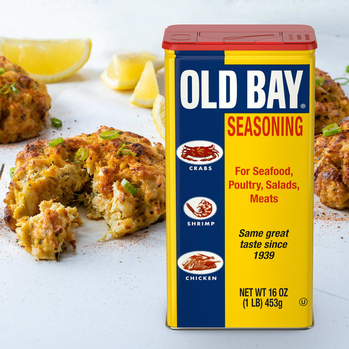 A container of Old Bay Seasoning with crab cakes in the background.