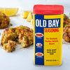 A container of Old Bay Seasoning with crab cakes in the background.