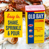 A can of Old Bay Seasoning with a red lid and a yellow label with a crab, shrimp, and chicken on it.