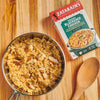 A bowl of Zatarain's Creamy Blackened Chicken with a wooden spoon on a wooden surface.