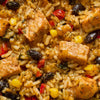 A close-up shot of a flavorful dish featuring rice, chicken, black beans, corn, and red peppers.