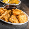 A plate of golden fried fish and chips is served with a dipping sauce, offering a delicious and satisfying meal.
