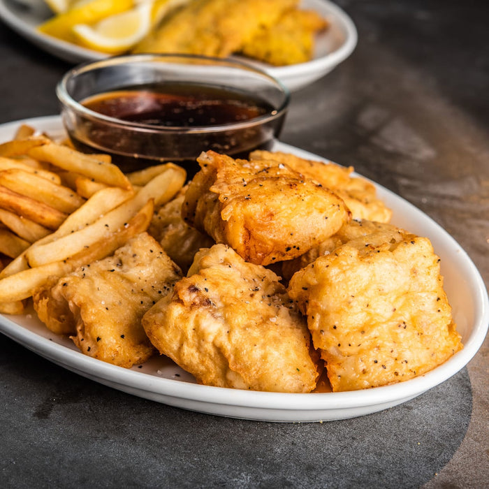 A plate of golden fried fish and chips is served with a dipping sauce, offering a delicious and satisfying meal.