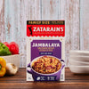 A box of Zatarains Jambalaya mix with a serving suggestion of peppers garlic and a bowl of the prepared dish.