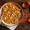 A red pot filled with jambalaya a Cajun and Creole dish made with rice shrimp chicken and vegetables.