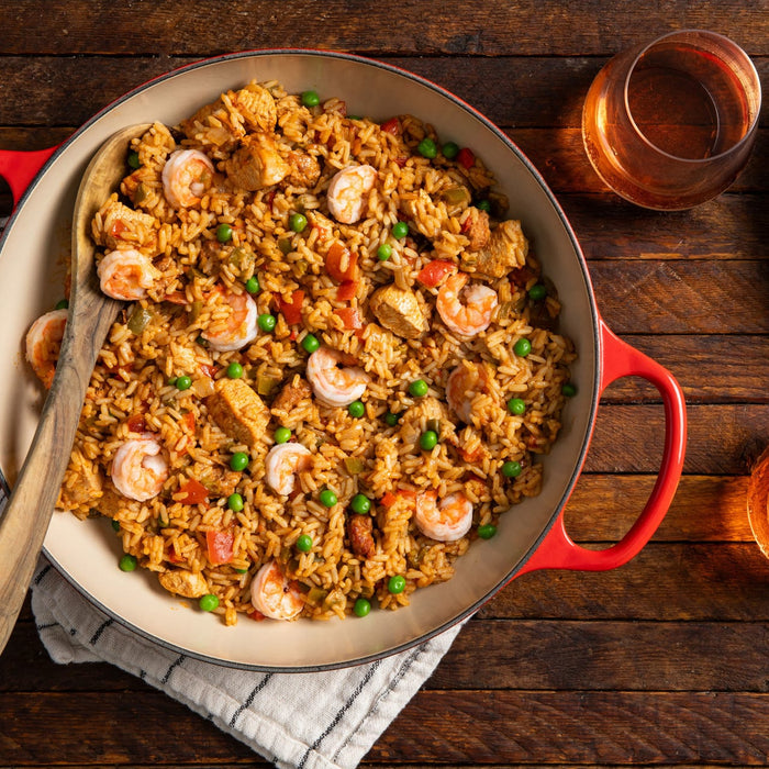 A red pot filled with jambalaya a Cajun and Creole dish made with rice shrimp chicken and vegetables.