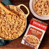 A box of Zatarain's Dirty Rice with a pot of cooked rice and a plate of rice.