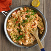A close-up of a pan of shrimp fried rice with green onions and red peppers.