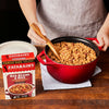 A person is holding a red pot of Zatarain's Red Beans &amp; Rice.