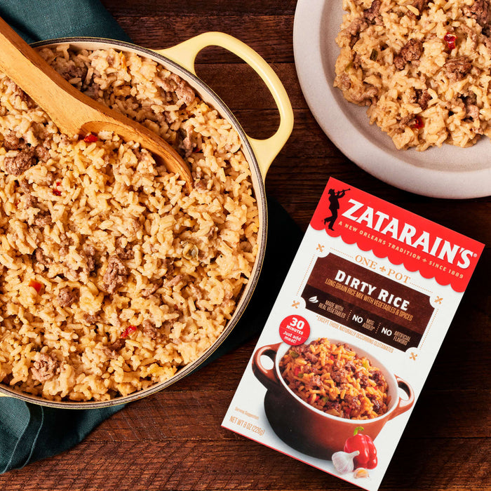 A box of Zatarains Dirty Rice mix is displayed next to a pot and plate of the cooked rice dish.